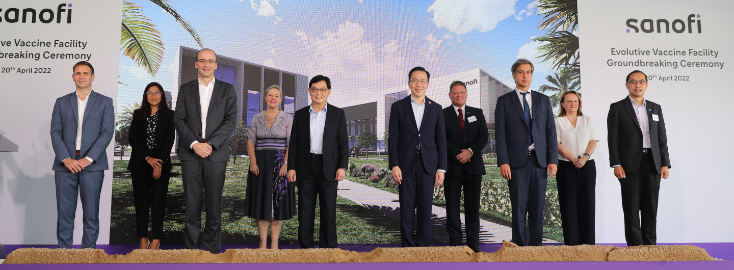 People at a Sanofi Evolutive Vaccine Facility Groundbreaking Ceremony in front of a rendering of a building.